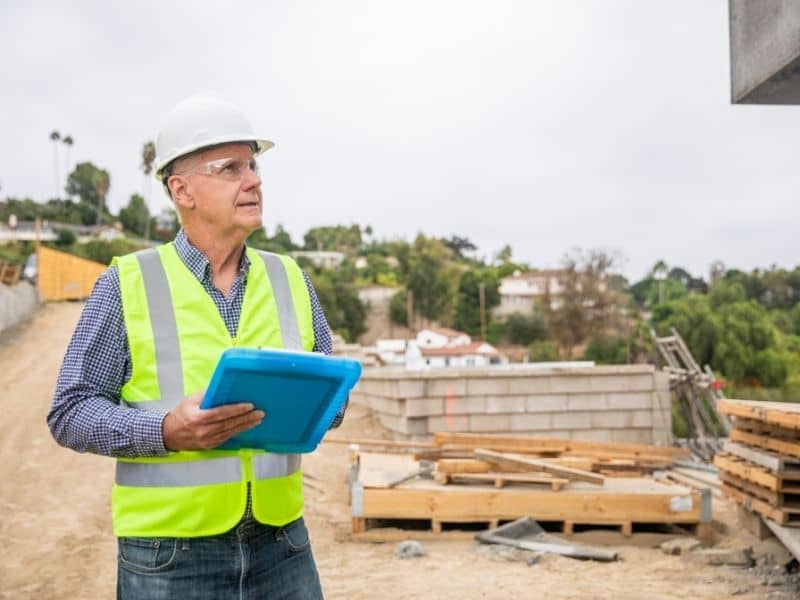 Survey professional reviewing residential construction site layout for subdivision development and neighborhood expansion planning.