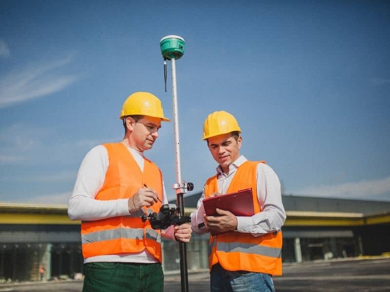 Construction surveyors using GNSS equipment to verify locations and elevations throughout a commercial building project.