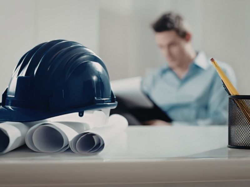 Hard hat and engineering documents on a desk for general site planning review