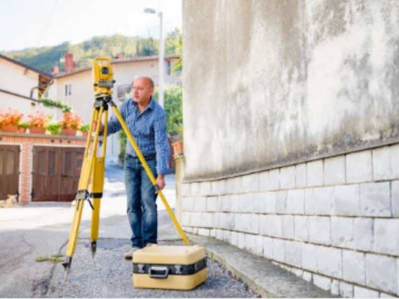 Residential land surveyor near me measuring property conditions near a detached garage in Fort Worth Texas